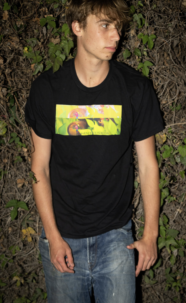 Model wearing black Smack Clothing tee in front of vines